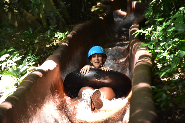 Smiling child on a tube sliding down a natural water slide in the forest