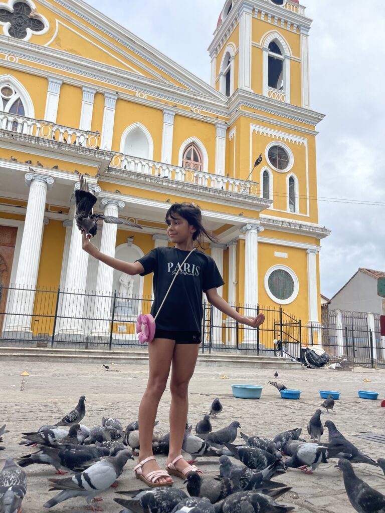 Child with pigeons in front of the Granada Cathedral, Nicaragua